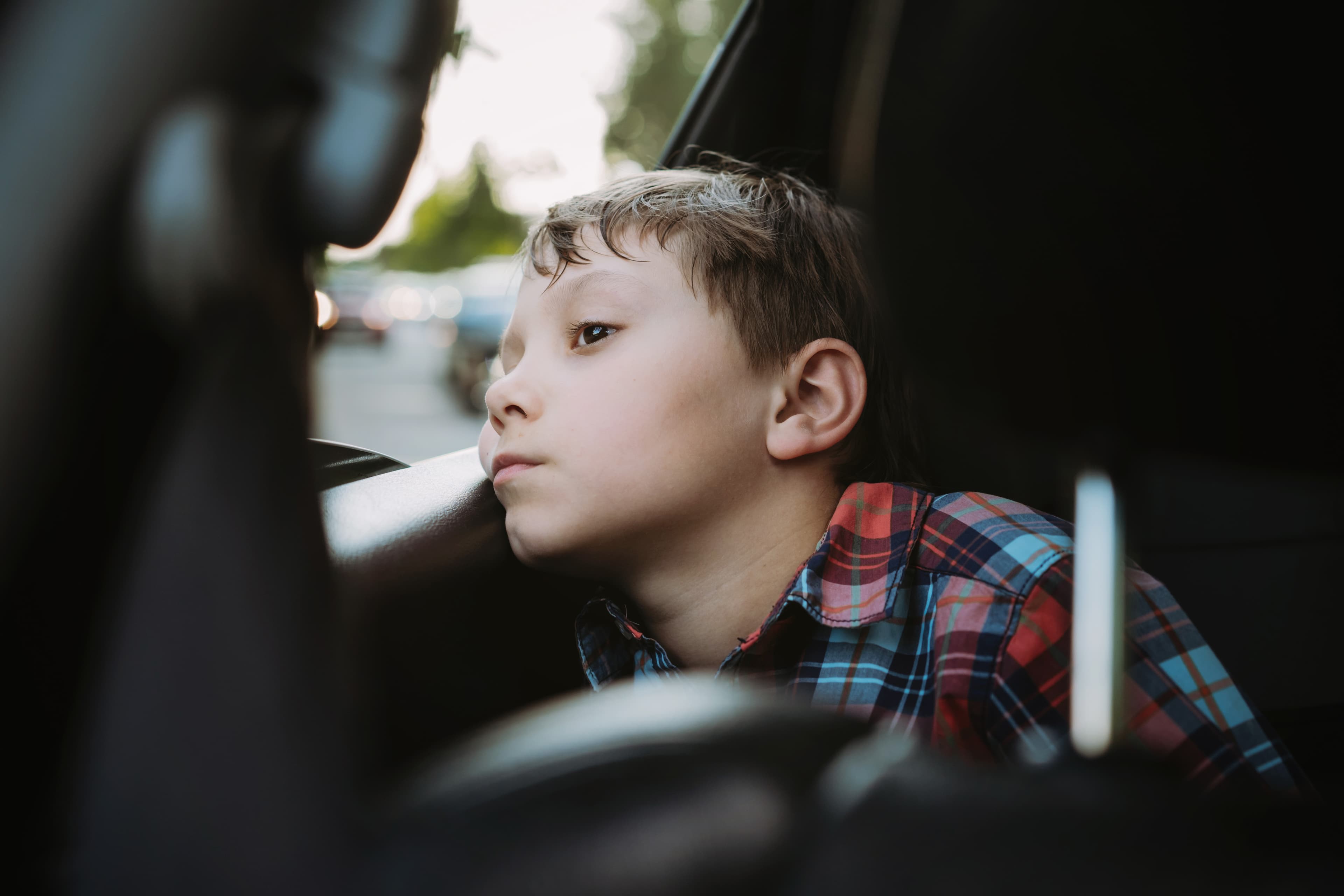 Child looking out car window, showing signs of anxiety