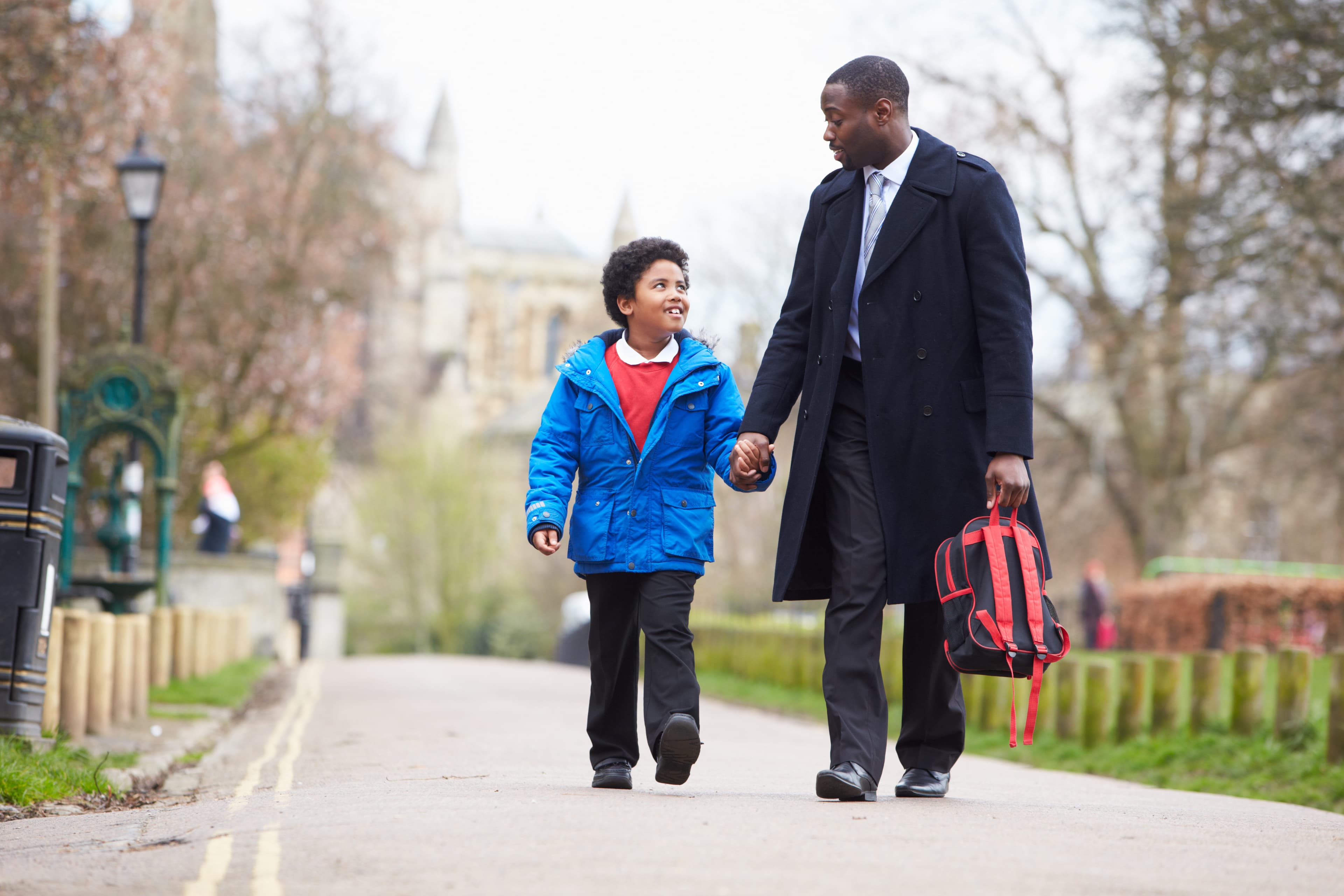 Father and son holding hands confidently walking to school